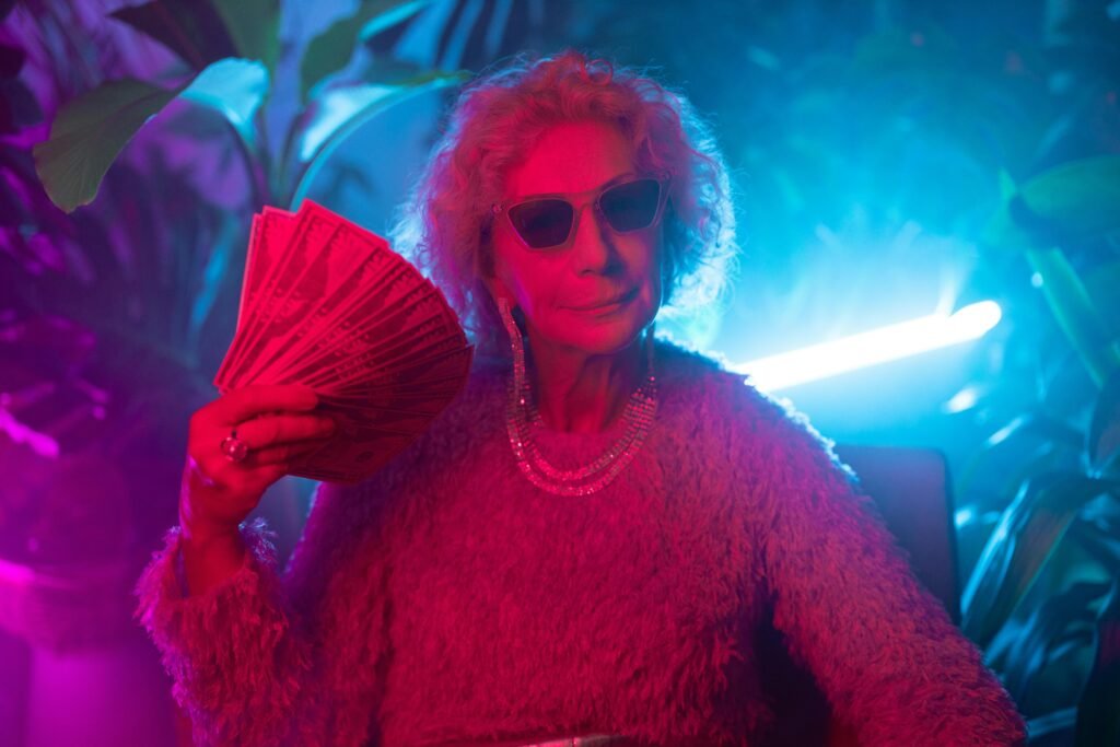 pexels-photo-7884134-7884134 An elderly woman exudes confidence and style under neon lights, holding a fan of cash.