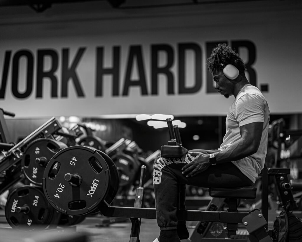 Black and white image of an athlete wearing headphones in a gym focusing on his workout.