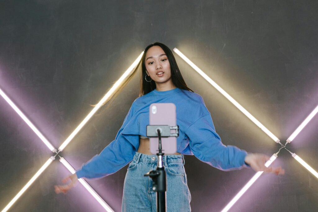 Why Many Agencies Are Moving Away from Human UGC & Content Creation 3 Teen influencer dances stylishly indoors, creating content using smartphone and ring light.